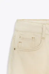 Jeans color crudo, de tiro alto, corte recto y largo tobillero. Con cinco bolsillos y cierre frontal con cremallera y botón.