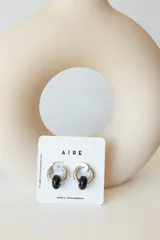 Aros de acero quirúrgico hipoalergénico con forma de argolla plateada y dije circular colgante de piedra natural color azul.