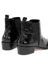 Bota corta negra de charol con textura tipo piel de cocodrilo, elásticos laterales, taco cuadrado y punta fina.