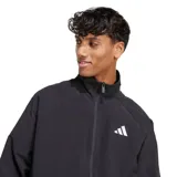 Campera deportiva Adidas de hombre, color negro, con cuello alto y cierre frontal. Presenta mangas raglán y el logo de Adidas Badge of Sport en blanco en el pecho izquierdo. El bajo y los puños son elásticos.