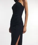 Vestido midi negro de bengalina, sin mangas, con breteles finos, escote halter, pliegues, abertura lateral y cierre por cremallera en la espalda.