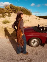 Bolso marrón de gamuza con flecos largos, asa de hombro y detalle de pasamanería con nudos.