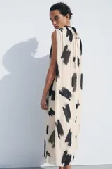 Vestido midi de Zara Woman Collection confeccionado en hilatura de viscosa color crudo con estampado abstracto en negro. Tiene cuello redondo, manga sisa, tejido plisado, forro interior y cierre en la espalda.