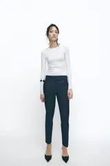 Pantalón tobillero azul oscuro, de tiro medio con cintura elástica en la espalda. Tiene bolsillos delanteros y falsos bolsillos de vivo en la parte trasera. El bajo está acabado con aberturas laterales.