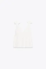 Top blanco con escote en pico y tirantes con detalle de lazos.