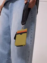 Billetera tarjetero negra de poliuretano con cierre y correa para colgar al cuello con logo Rusty estampado.