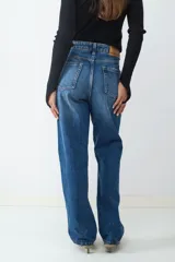 Pantalón de jean de tiro medio, corte recto, con diseño clásico de cinco bolsillos, cierre de cremallera y botón metálico.