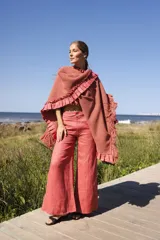 Ruana tejida artesanalmente en lana merino con detalles en lino teñido artesanalmente. Presenta textura de punto waffle en el cuerpo principal y volados con flecos en los bordes.