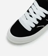 Championes negros de estilo skater con cordones gruesos blancos, suela blanca y detalles de líneas curvas blancas en los laterales.