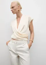 Blusa de tejido fluido con diseño cruzado y cuello en V, sin mangas y sin cierre.