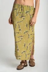 Falda midi color verde oliva con estampado de ramas y hojas en tonos grises y blancos. Tiene cintura elastizada con cordón ajustable y un tajo lateral.