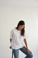 Remera blanca de algodón con estampado de un sol con gafas de sol y una tabla de surf.