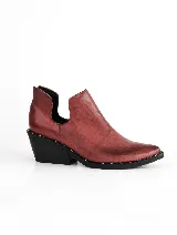 Botín negro de cuero vacuno con punta fina, taco cuadrado y detalle de tachas plateadas en el borde de la suela.