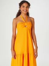 Vestido largo naranja con escote halter y detalle de nudo en el pecho.