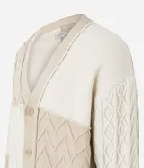Cardigan de punto beige con diferentes texturas y bloques de color. Tiene cuello en V, abotonadura frontal y mangas largas.
