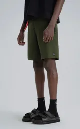 Short de baño color verde militar, confeccionado en microfibra de secado rápido. Presenta cierre frontal con cordón y velcro, y tres bolsillos con cierre (uno en cada lateral y uno trasero).