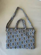Bolso para laptop con estampado de árboles en tonos azules y crema, con asas cortas y strap ajustable.