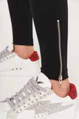 Calza negra de tiro alto, corte ajustado y largo hasta el tobillo. Presenta cierre metálico en los tobillos.