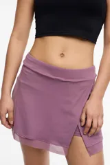 Short deportivo color lila con calza interna y bolsillo lateral. Presenta un frente cruzado y detalle de microtul.