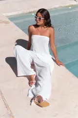 Conjunto de dos piezas color beige claro, compuesto por un top strapless con bajo asimétrico y un pantalón ancho de tiro alto.