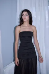 Vestido strapless negro con lunares blancos, confeccionado en jersey elastizado, con fruncido en laterales, y falda larga de gasa fruncida.