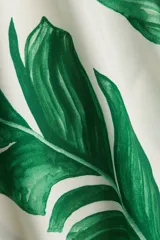 Vestido túnica corto de viscosa con estampado de hojas verdes, cuello mao con abertura en V, mangas cortas, corte holgado y tajos laterales.