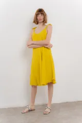 Vestido corto amarillo de lino, con escote en V y tirantes finos con detalle de moño en los hombros.