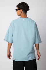 Remera negra oversize con mangas cortas y costuras a la vista en color blanco.