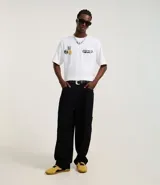 Pantalón negro de sarga, corte skater, con bolsillos grandes y recortes deslocados.