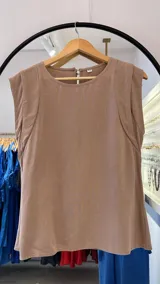 Musculosa sin mangas color tostado, con cuello redondo y un corte ligeramente holgado que cae en A. Presenta un detalle de costura curva que define la sisa y el hombro.