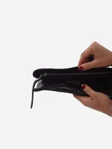 Sobre de fiesta negro charolado con cierre de solapa imantada y tira de cuero para sujetar a la muñeca.