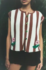 Chaleco tejido a rayas verticales marrones y celestes, con bordado artesanal de una flor en el frente y cierre con botones.