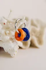 Aros colgantes de acero quirúrgico con dos dijes circulares de cristal de Murano, uno color naranja y otro azul.