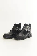 Botas cortas negras de cuero con punta cuadrada, detalle de hebilla metálica y suela track.