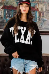 Sweater negro de felpa con la palabra "TEXAS" estampada en blanco en el frente.
