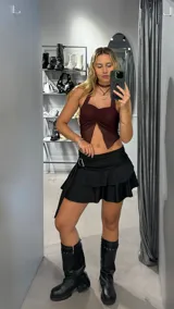 Minifalda negra de tiro bajo con volados y detalle de hebilla metálica en la cintura.