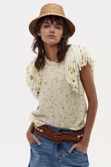 Chaleco tejido plano color crudo, sin mangas, con flecos bordados a mano en los hombros.