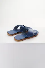 Sandalias bajas de cuero azul con tiras anchas cruzadas sobre el empeine y suela plana color madera.