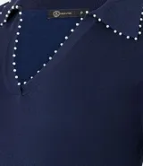 Blusa de punto color blanco, con cuello polo, escote en V y mangas cortas. Detalle de mini perlas aplicadas en el cuello.