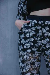 Conjunto de tres piezas con estampado floral blanco sobre fondo negro, compuesto por un top bandeau negro, una camisa de manga corta con cuello solapa y un pantalón largo de corte recto.