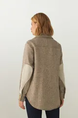 Camisa estilo leñador color beige con textura de espiga, de manga larga con puños abotonados, cuello clásico, cierre frontal con botones y dos bolsillos de parche con solapa abotonada en el pecho.