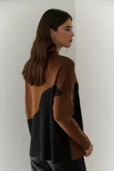 Buzo de punto con diseño geométrico en bloques de color gris y negro, de cuello redondo y mangas largas.
