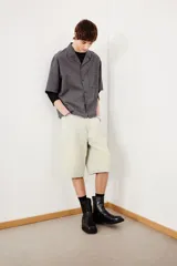 Camisa de manga corta en sirsaca de algodón a rayas grises y negras. Modelo boxy con cuello abierto, tapeta lisa, bolsillo superior y bajo recto. Corte holgado.