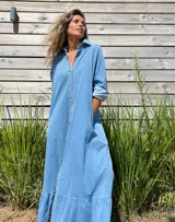 Vestido camisero largo de jean celeste con botones frontales, cuello camisero y volado en el ruedo.