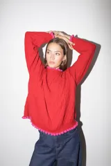 Sweater tejido rojo con cuello alto y puños con volados azules.