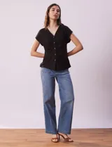 Remera blanca de lino, marca Zac & Rachel, con escote en V, abertura con botones y frunce en la parte delantera.