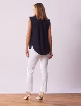 Blusa negra de gasa marca Tahari, con cuello a la base con solapa, abertura central con botones ocultos y detalle plisado en hombros.