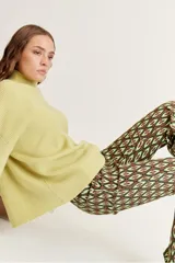Pantalón acampanado con estampado geométrico en tonos marrón, verde oliva y verde claro.