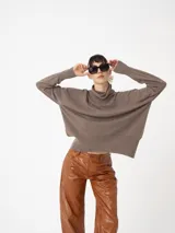 Sweater de tejido fino color tostado, con cuello alto y silueta amplia, perfecto para los días fríos.