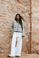 Campera corta acolchada de algodón con estampado floral en blanco y negro, cuello redondo, cierre frontal con botones a presión, bolsillos delanteros de parche y forro de algodón.